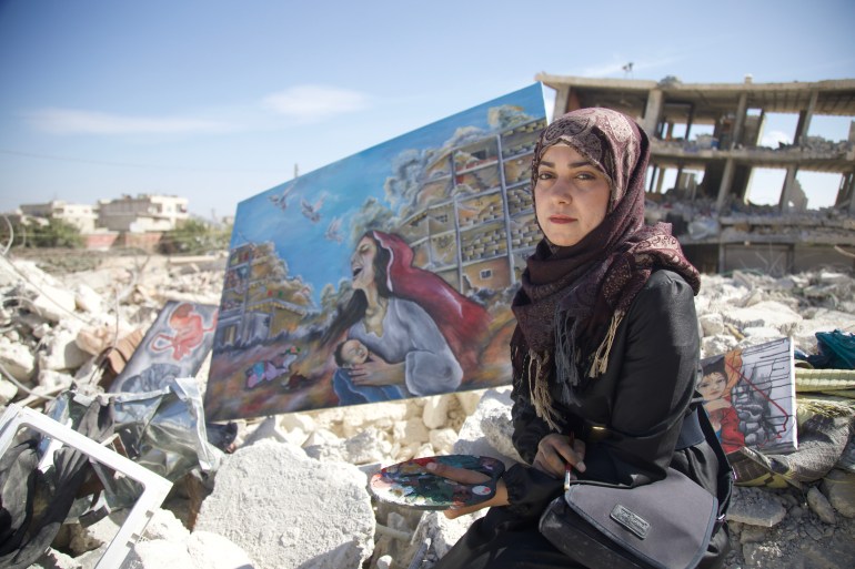Artist Yasmine Khalil sits with her artworks in the rubble