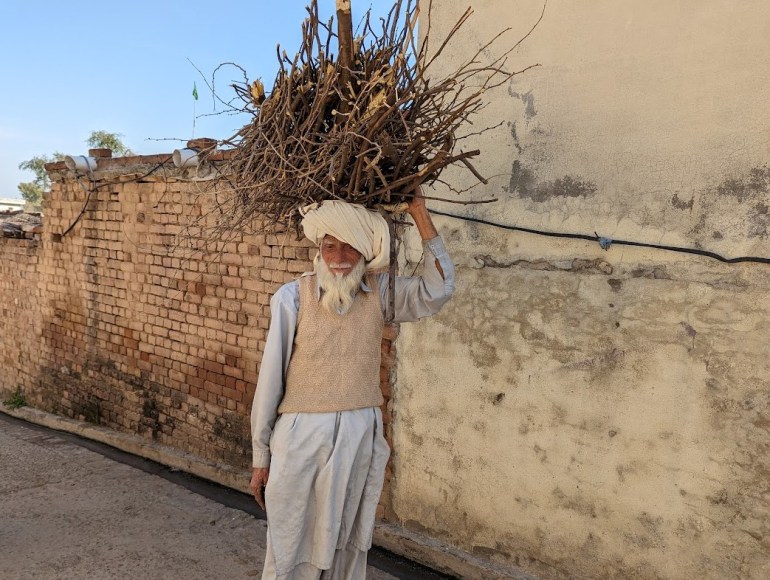 A photo of a man carrying firewood on his head.