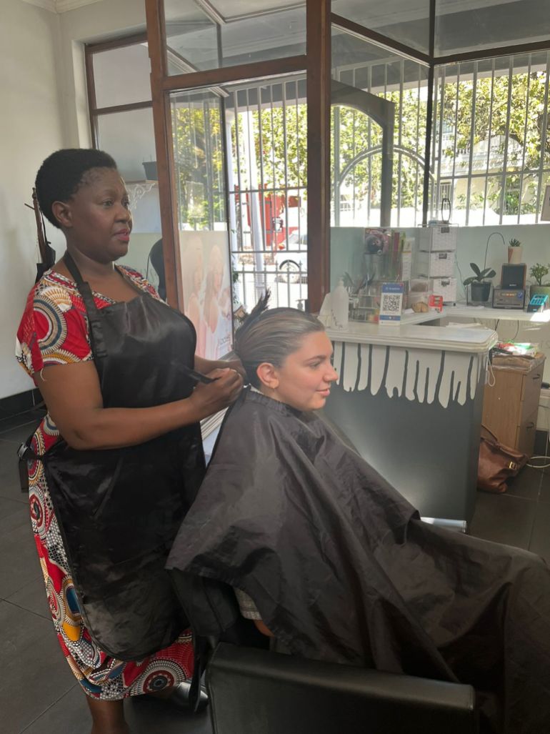 A photo of Mavis Namba working at her hair salon.