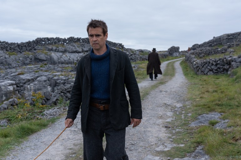 Colin Farrell walks down a stone-lined country road, as his co-star Brendan Gleeson walks in the opposite direction.