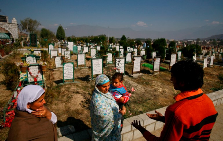 A Kashmiri family visits the grave of their relative at a graveyard during Eid-al-Fitr celebrations in Srinagar [File: EPA Images]