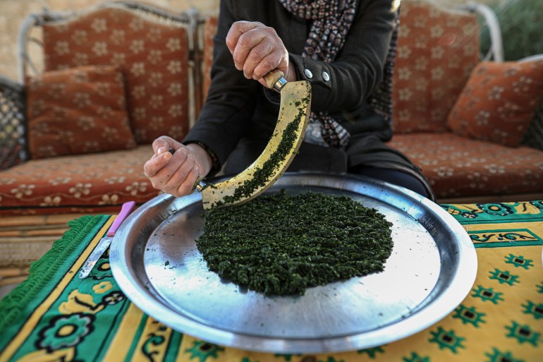Siham uses a makhrata to grind the leaves, referring to a double-handled knife with a curved blade, similar to the Italian mezzaluna
