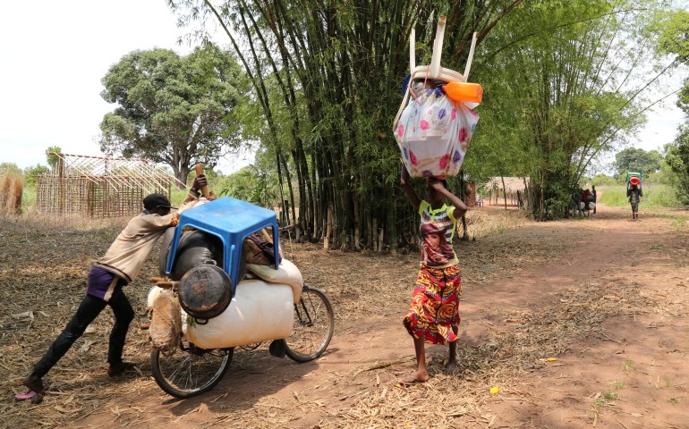 Congolese migrants expelled from Angola push a rented bicycle to transport their belongings along the dirt road to Tshikapa, Kasai province near the border with Angola, in the Democratic Republic of the Congo