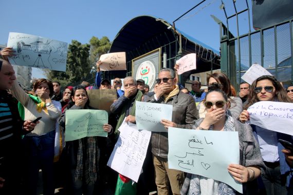 Journalists working at state media carry banners and cover their mouths during a protest in front of the state TV building to demand freedom to cover mass protests against President Abdelaziz Bouteflika, in Algiers, Algeria March 25, 2019. The banners read: "We are all concerned", "The camera doesn't lie" and "For a public television free and open for all". REUTERS/Ramzi Boudina