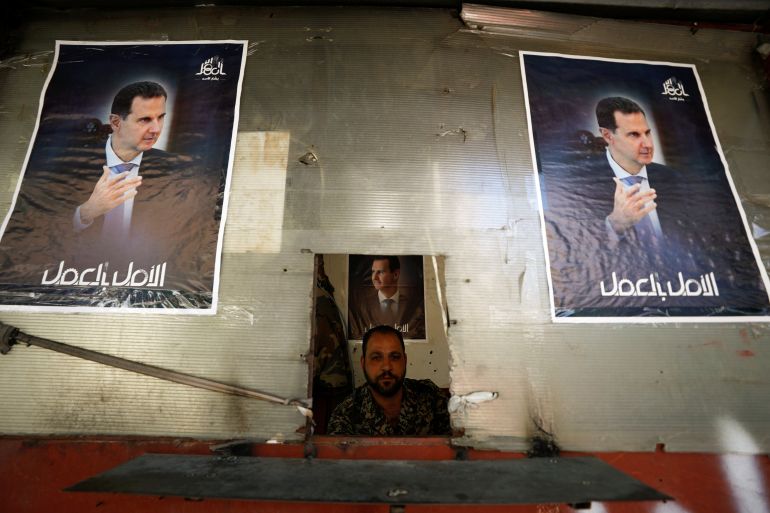 A Syrian soldier sits near posters depicting Syria's President Bashar al-Assad, during the country's presidential elections at a checkpoint in Damascus, Syria.