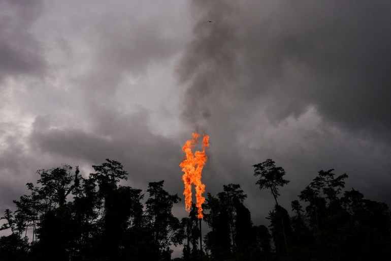 A gas flare, with shooting red flames, erupts above an Ecuador forest