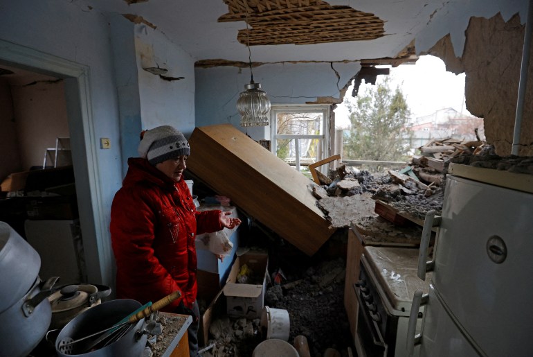 A woman stands in a destroyed kitchen