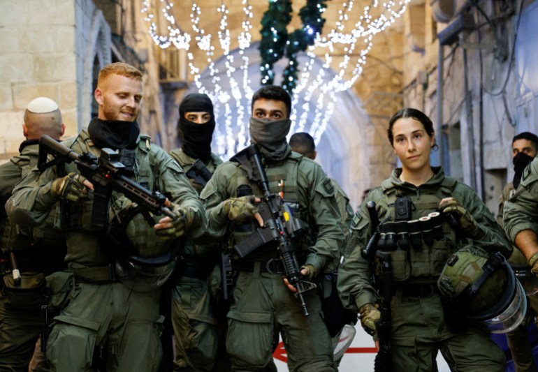 Israeli police seen in an alleyway with twinkle lights overhead