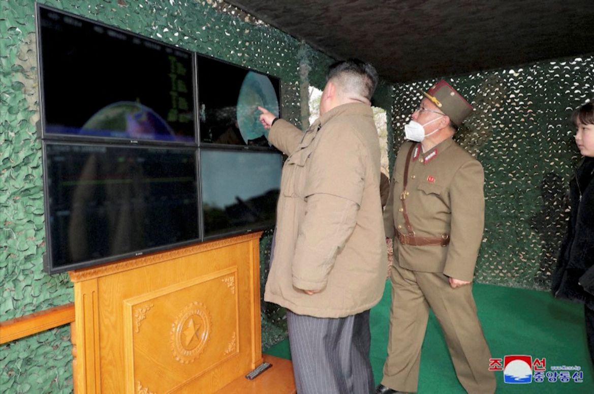 Kim Jong Un with his military officials pointing out something on a screen.