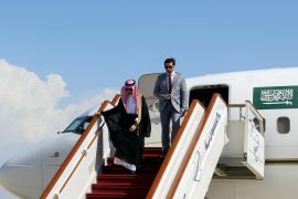 Prince Faisal bin Farhan walks down the airplane stairs