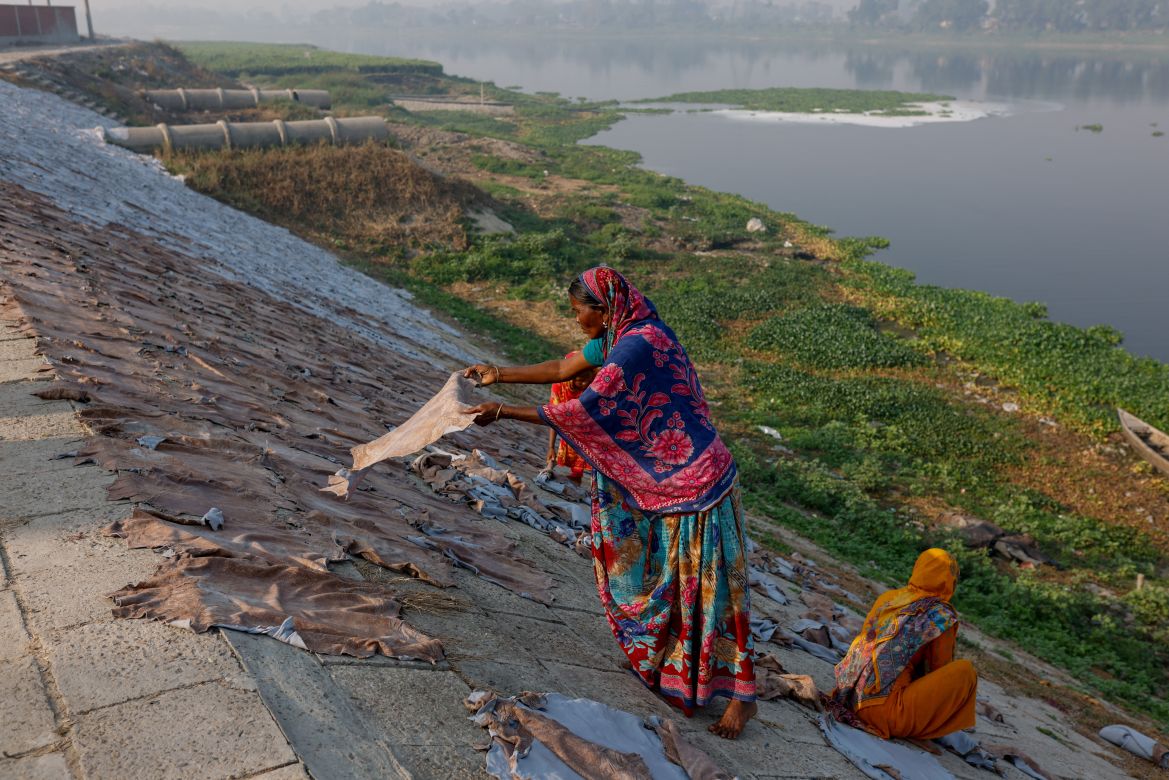 Women dry cattle hides outside of a tannery by the Dhaleshwari river, which feeds into the Buriganga river,