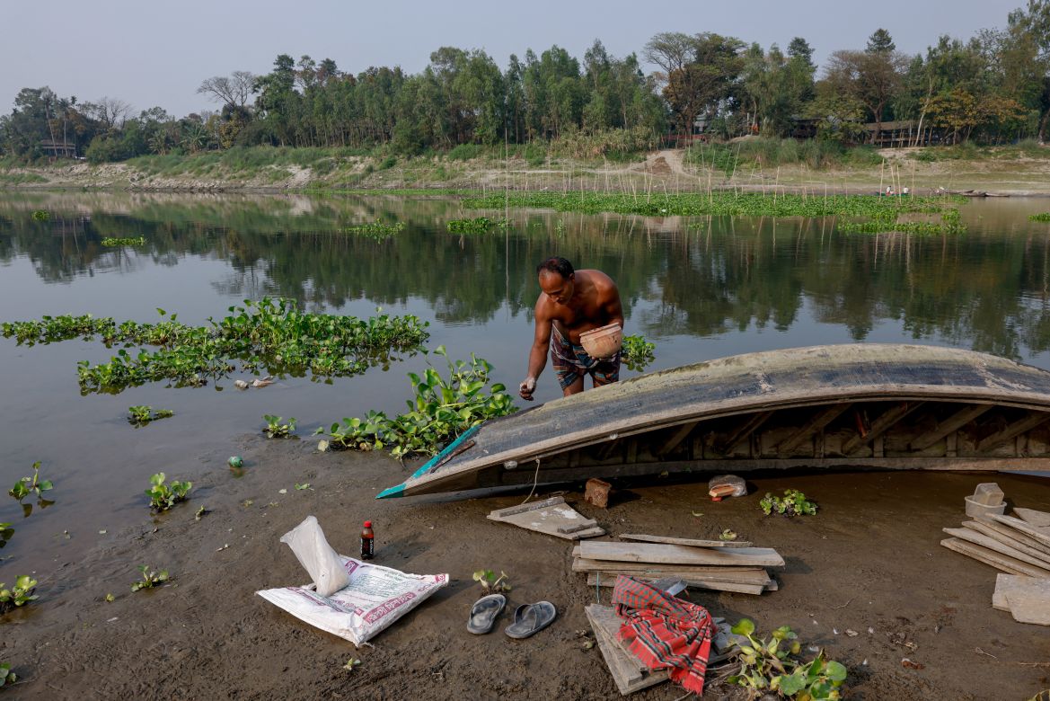 Construction worker Somej Mia, 40, repairs his boat on the bank of the Bangshai river