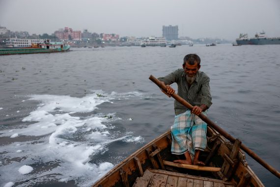 White foam is formed in the water as ferryman Abdul Karim, 72, rides his boat in the Buriganga river near the Sadarghat area in Dhaka