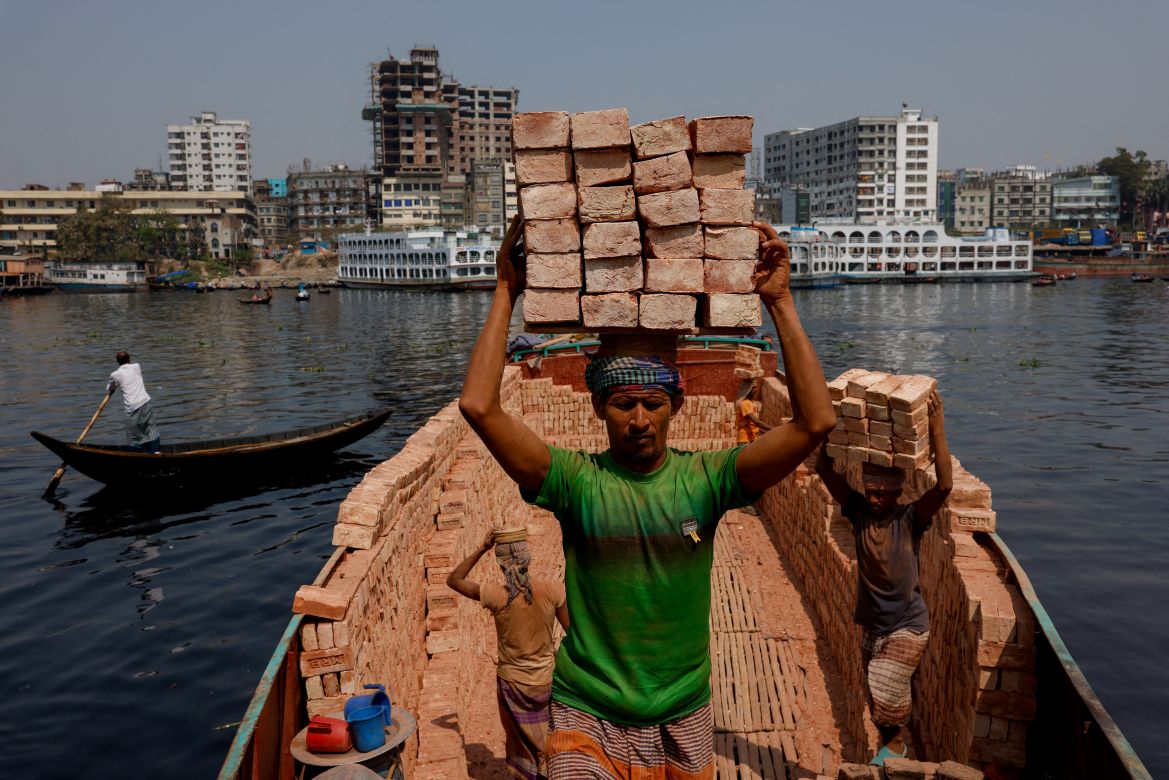 Labourers unload bricks from a trawler on the bank of the Buriganga river in Dhaka