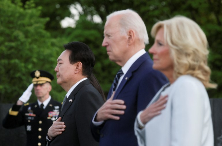 South Korean President Yoon Suk-yeol, US President Joe Biden and First Lady Jill Biden stand in a row with their hands over their hearts
