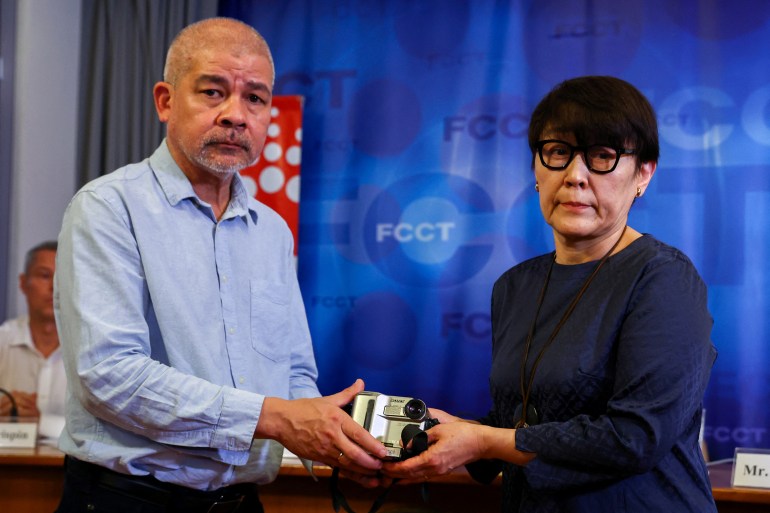 Noriko Ogawa, sister of slain Japanese journalist Kenji Nagai, receives her brother's lost videocamera from Aye Chan Naing, co-founder of the Democratic Voice of Burma (DVB), during an event to release unseen footage he filmed before being killed during the coverage of the 2007 Saffron Revolution in Yangon, at the Foreign Correspondent's Club of Thailand in Bangkok, Thailand, April 26, 2023. REUTERS/Athit Perawongmetha