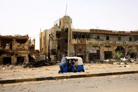 People pass by damaged cars and buildings at the central market during clashes between the paramilitary Rapid Support Forces and the army in Khartoum, North, Sudan.