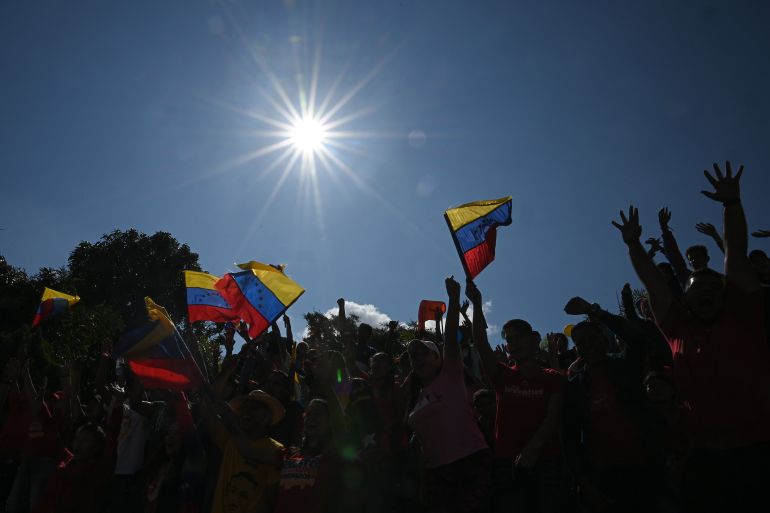 Supporters of Venezuelan President Nicolas Maduro wave national flags as they take part in a march on International Youth Day in Caracas, on February 12, 2023. (Photo by Federico PARRA / AFP)