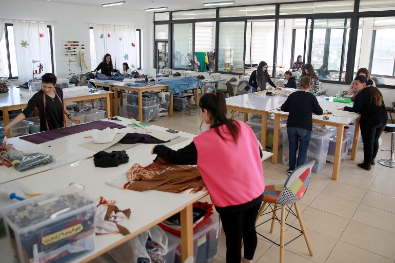 View of the atelier's workshop with about 10 women working at various worktables.