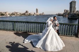a couple poses before a video cameraman for their wedding video along a bridge by the Nile