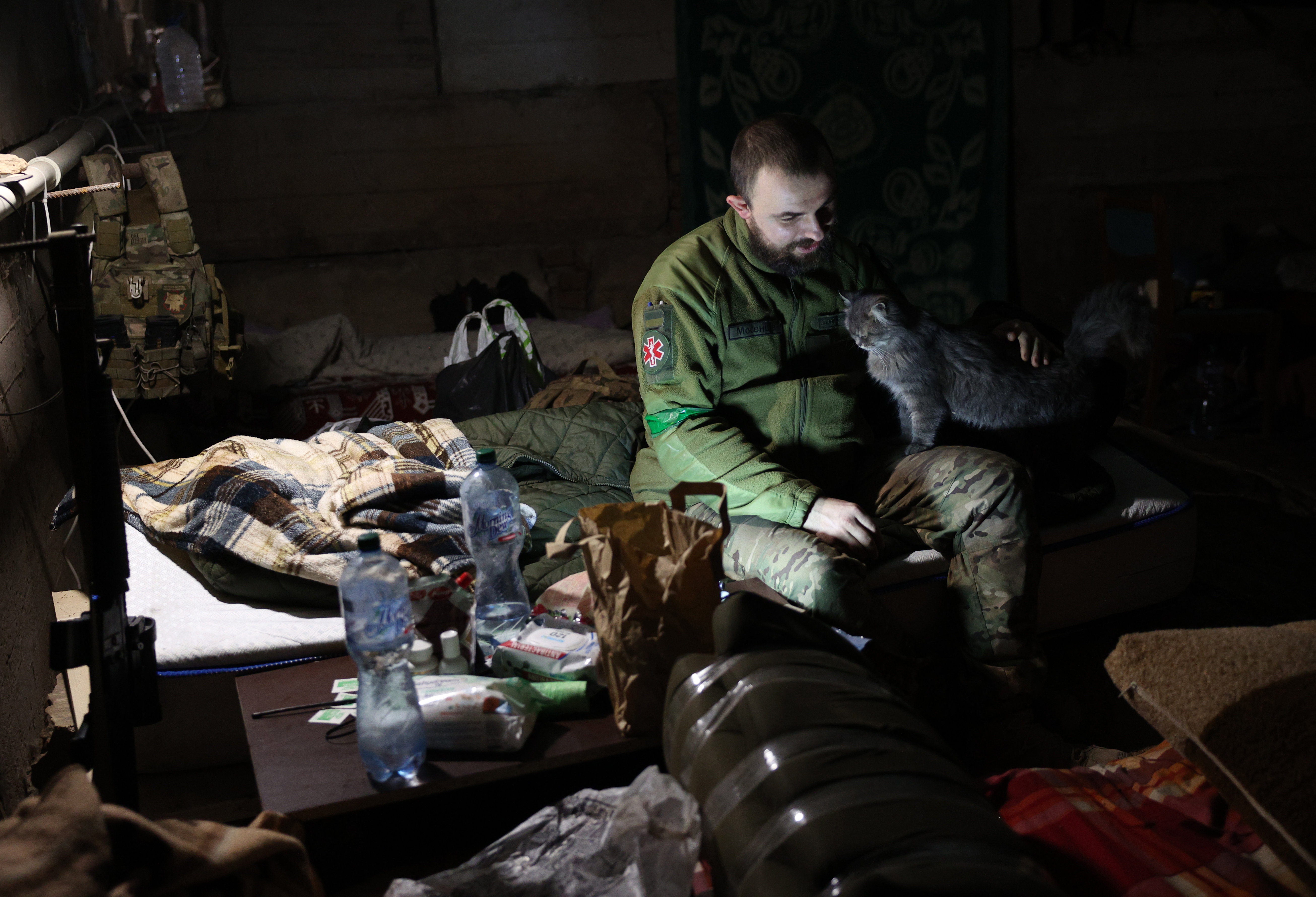 A military paramedic pets a cat in a bomb shelter in the frontline city of Bakhmut