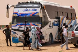 People disembark off a passenger bus at the Multaga rest-stop near Ganetti in Sudan's Northern State
