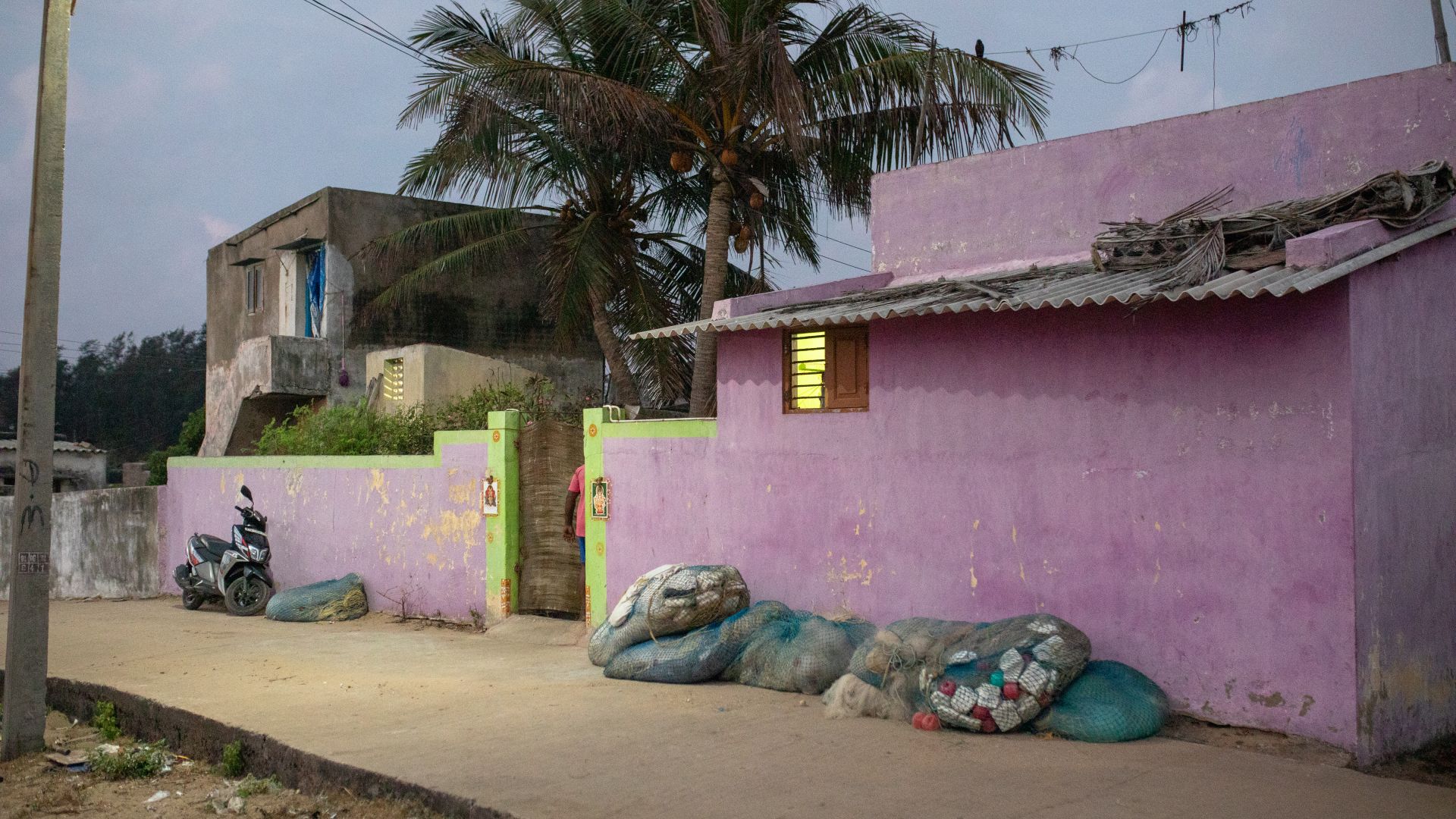 A photo of a house with bags of garbage on the wall outside.