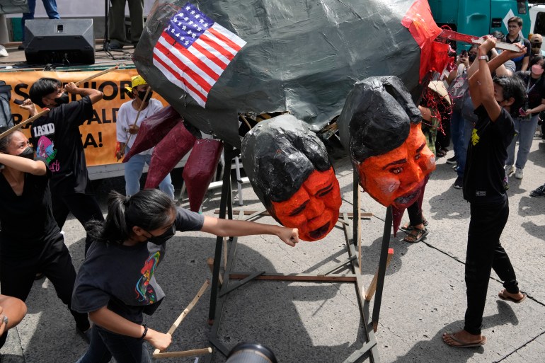Demonstrators punch an effigy of Ferdinand Marcos Jr. It is also painted with a US flag.