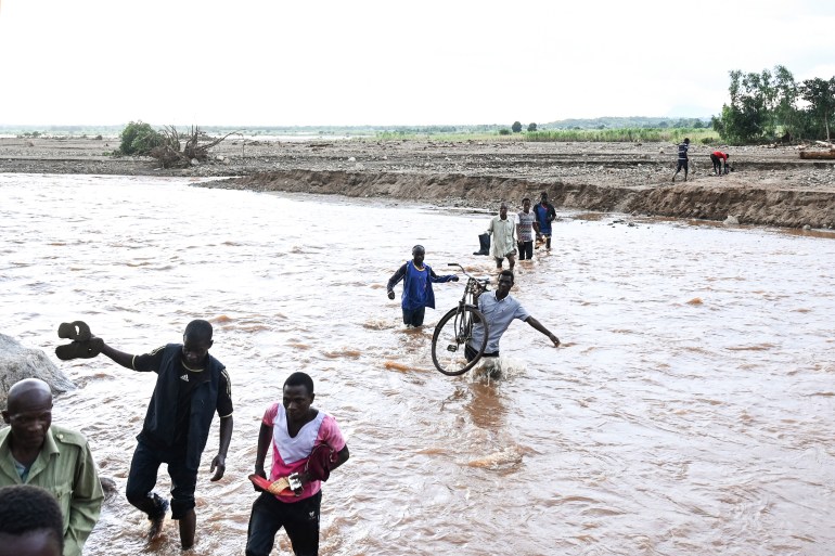 FILE - People wade through floodwaters in the aftermath of Tropical Cyclone Freddy in Phalombe, southern Malawi on March 18, 2023. During a conference in the Ethiopian capital of Addis Ababa on Monday, March 20, 2023, leaders of African countries hit hard by climate change discussed finance options that would allow for the forgiveness of debt in exchange for investment in green energies. (AP Photo/Thoko Chikondi, File)