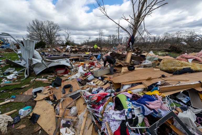 FILE - People walk through damage from a late-night tornado in Sullivan, Ind., April 1, 2023. (AP Photo/Doug McSchooler, File)