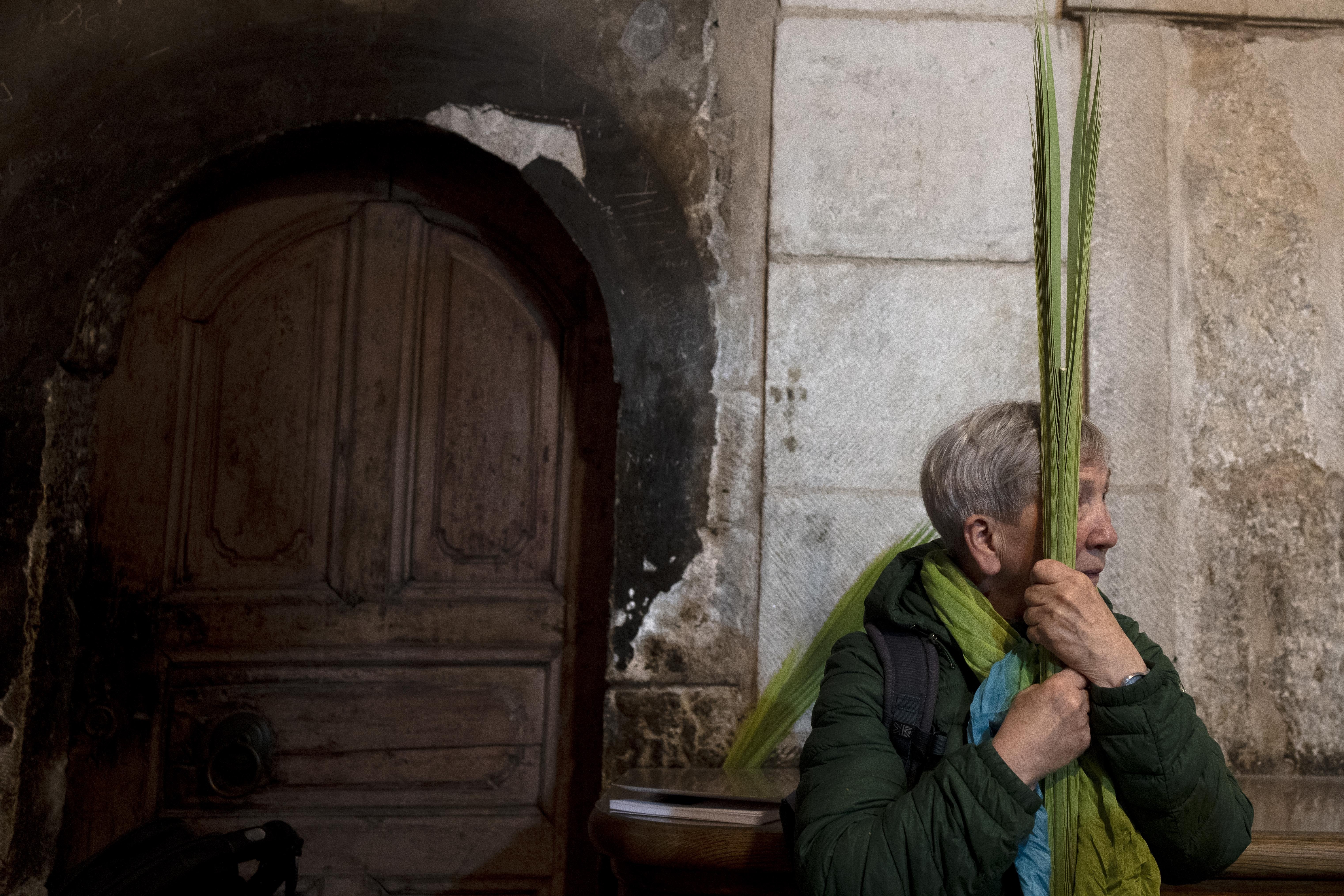 A woman holds palm fronds during Palm Sunday Mass