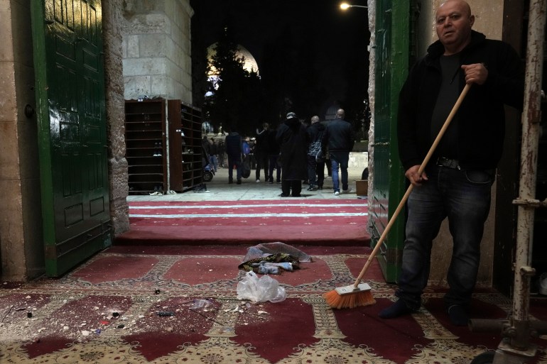 A Palestinian worshipper sweeps debris after a raid by Israeli police at the Al-Aqsa Mosque.