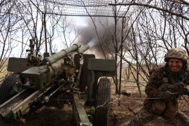 A Ukrainian soldier turning away after firing a howitzer at Russian positions near the frontline in Luhansk