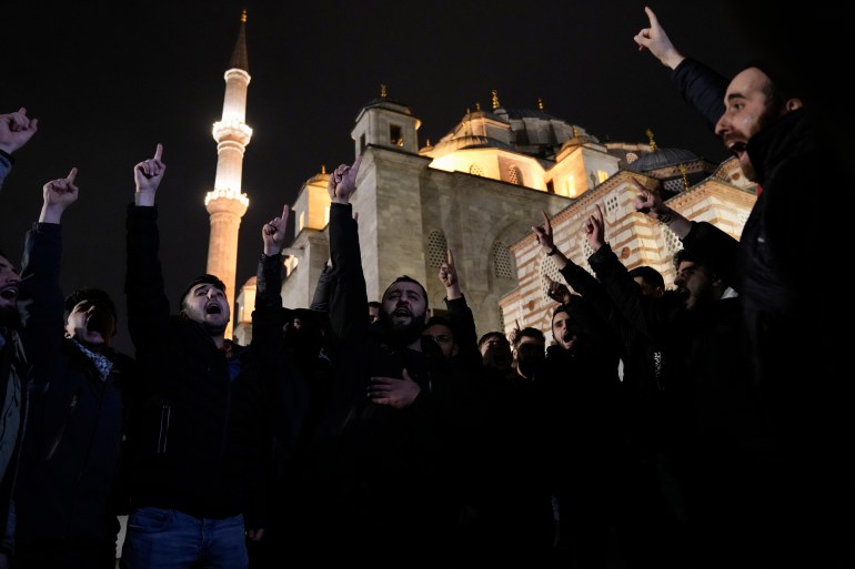 People in Istanbul are silhouetted against the light of a mosque in the background