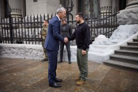 Jens Stoltenberg and Volodymyr Zelenskyy shaking hands on the street in Kyiv