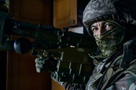 A Ukrainian soldier looks at the camera while holding a rocket launcher in Bakhmut, in the Donetsk region, Ukraine, Wednesday, April 26, 2023. His face is covered with a military mask [Libkos/AP]