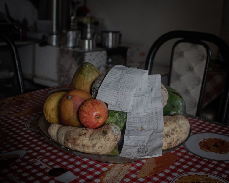 A photo of fruits and vegetables on a table with a long receipt folded on top of them.