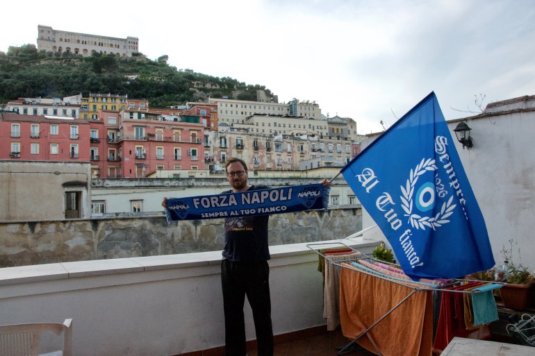Andrea Bartolo, a lifelong fan of Napoli, stands with his Napoli banner and flag on his balcony in the Spanish Quarters neighbourhood. The neighbourhood is one of the most lively and patriotic in the city boasting tiny streets filled with Napoli memorabilia.