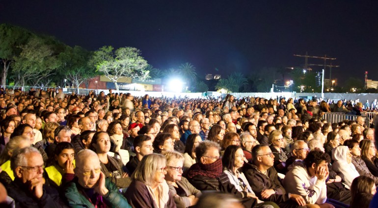 A mostly Israeli audience listening to bereaved Israelis and Palestinians speak in a park at night