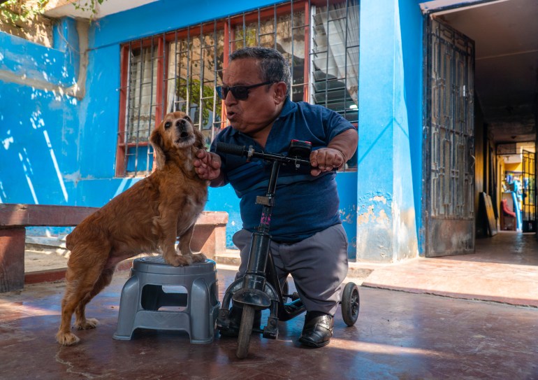 A man plays with his cocker spaniel in the courtyard of a blue house in Peru