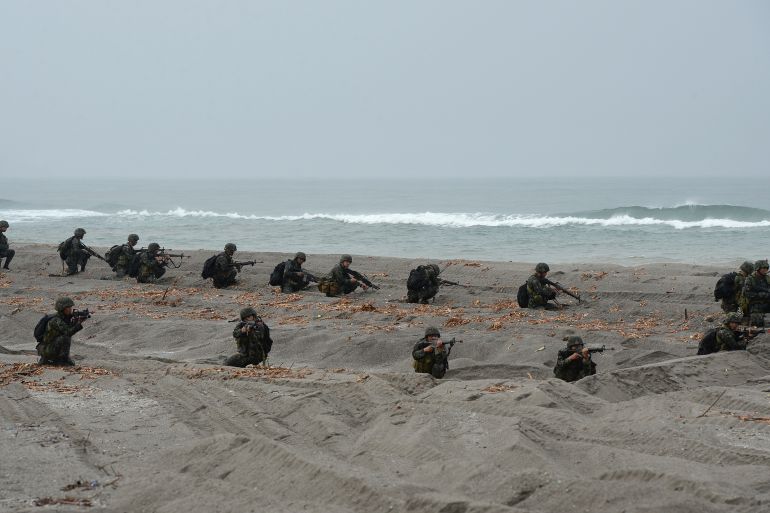 Philippine Marines take their position during a mock beach assault along with their US counterparts as part of Cooperation Afloat Readiness and Training (CARAT 2014) along the beach at a Philippine naval training base facing the South China Sea in San Antonio, Zambales province, north of Manila on June 30, 2014. Naval forces from the US and Philippines engaged in an amphibious landing on June 30 on Luzon island amid a tense territorial row with China. AFP PHOTO / TED ALJIBE (Photo by TED ALJIBE / AFP)