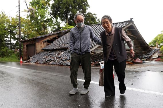 Residents walk past their collapsed house after a magnitude 6.5 earthquake hit the town of Suzu a day earlier, in Ishikawa Prefecture, central Japan, 06 May 2023.