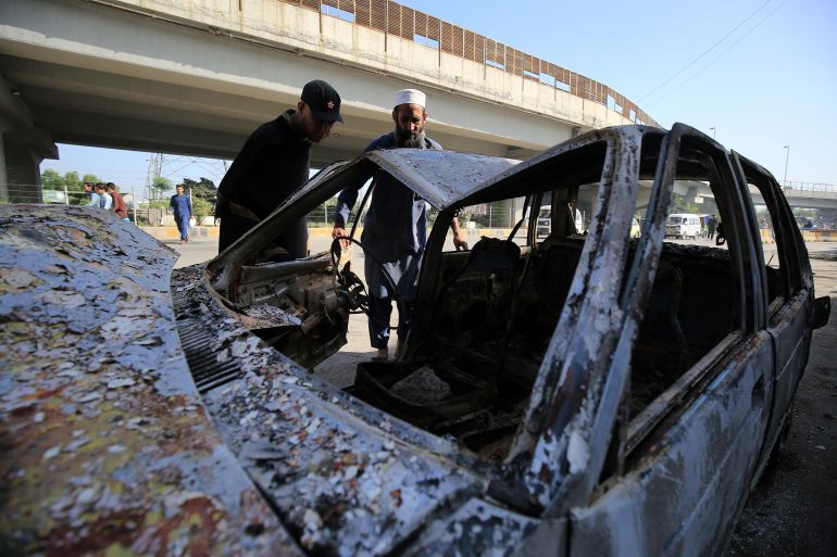 epa10618566 People check a burnt vehicle a day after violent protests broke out across the country following the arrest of Imran Khan, former prime minister and head of the opposition party Pakistan Tehrik-e-Insaf, in Peshawar, the provincial capital of KPK province