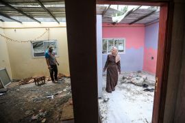 Aisha and her husband Suliman in their home in Gaza that was badly damaged after a nearby building was hit by Israel on May 13 [Abdelhakim Abu Riash/Al Jazeera]