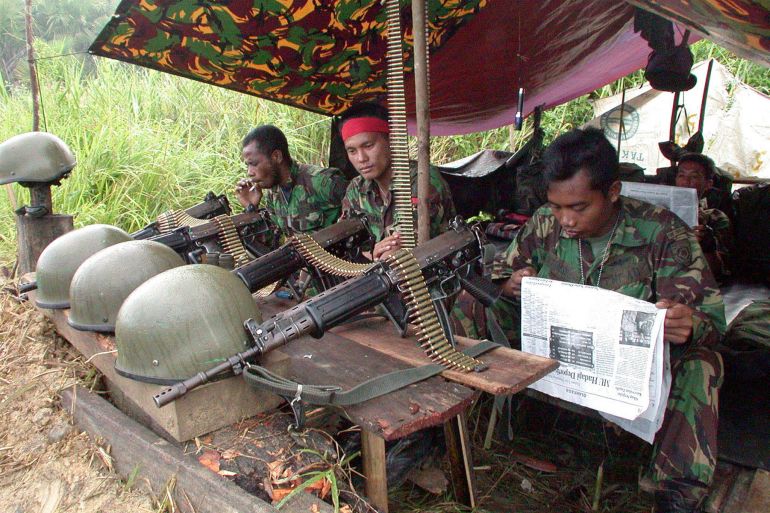 Indonesian soldiers in a shelter during the Aceh conflict in 2002. They have taken their helmets off and laid their weapons on the table in front of them