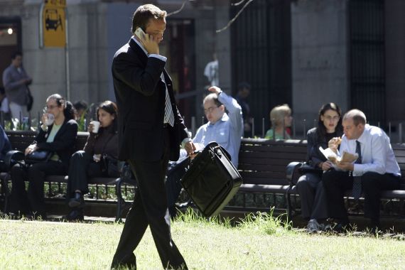 A businessman talks on his mobile phone as other office workers have lunch in a central Sydney park April 3, 2006