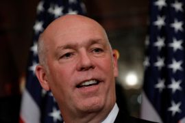 A close-up of Greg Gianforte against a row of American flags
