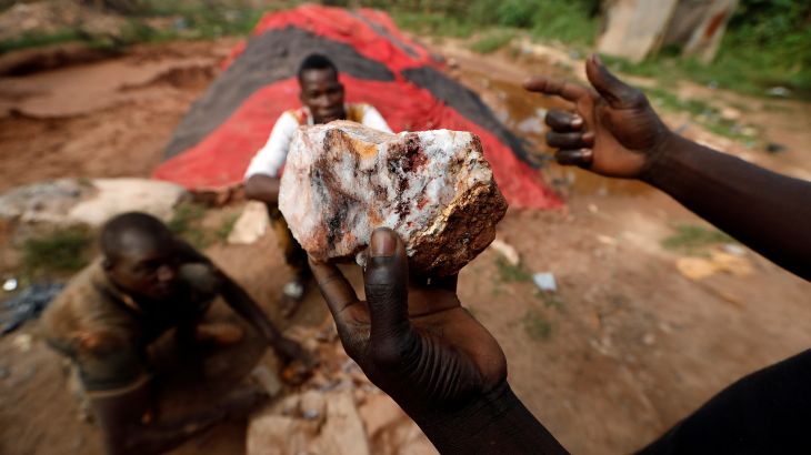 An informal gold miner holds up a rock recovered from inside a gold mine before it is ground down for processing at the site of Nsuaem-Top, Ghana