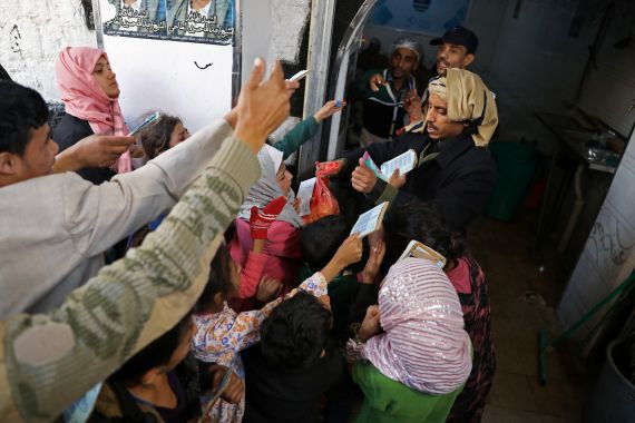 People reaching out for food aid being given from a charity kitchen in Yemen.