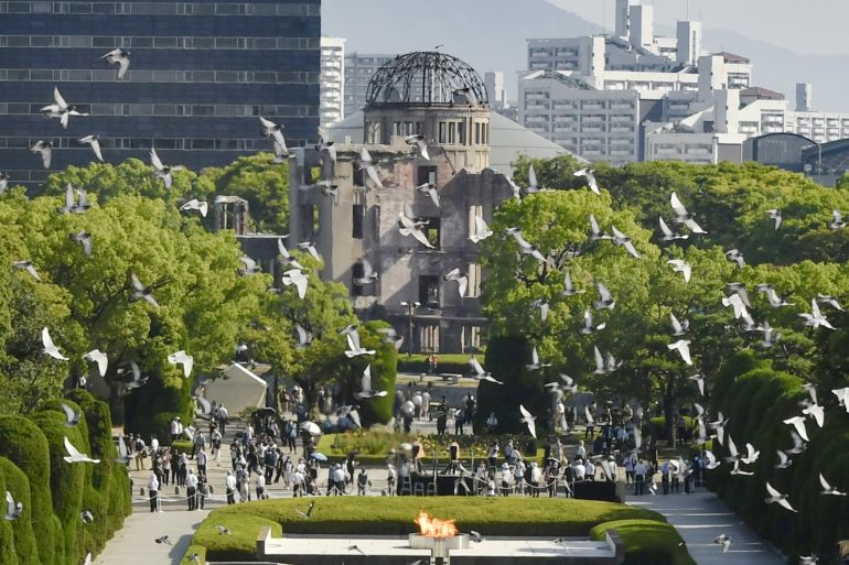 Birds flying in the Hiroshima Peace Park with the ruined Atomic Bomb Dome behind.